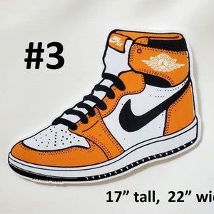 May include: A cartoon illustration of an orange and white basketball shoe with a black swoosh and a gold "Air Jordan" logo. The shoe is 17 inches tall and 22 inches wide.