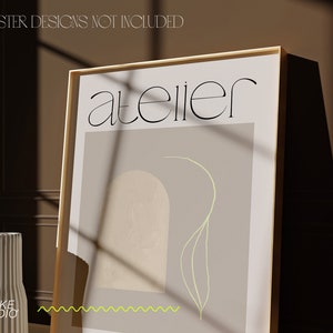 May include: A framed poster with a light brown background and a light green line drawing of a plant. The text "atelier" is printed in black at the top of the poster.