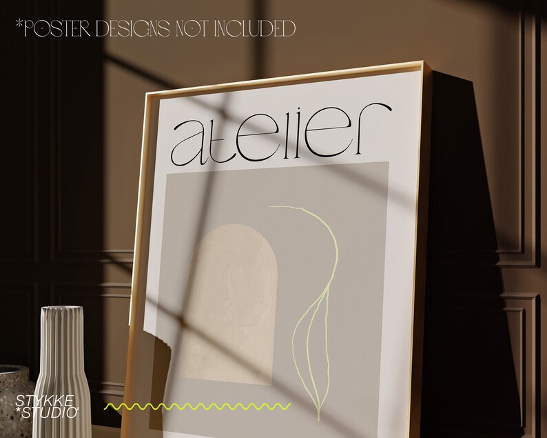 May include: A framed poster with a light brown background and a light green line drawing of a plant. The text "atelier" is printed in black at the top of the poster.