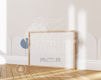 May include: A wooden frame mockup with a white background and a light wood floor. The frame is empty and ready for your design. The text "Styled Mockup Scene Essential Frame Stykke Studio" is printed on the frame.