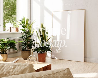 May include: A large, white framed poster mockup in a living room setting with a wooden floor, a coffee table, and several potted plants. The poster is blank and ready for your design.