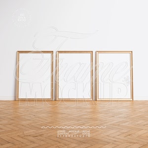 May include: Three gold picture frames with white mounts are hanging on a white wall. The frames are empty and ready for your photos or artwork. The frames are in a modern style and would look great in any home.