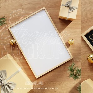 May include: A wooden frame mockup with a white background, surrounded by brown gift boxes with bows, gold bells, and pine sprigs on a wood surface.