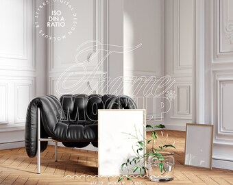Può includere: Un mockup di cornice bianca con cornice in legno, appoggiato su un pavimento in legno in una stanza con pareti bianche e una poltrona in pelle nera. La cornice è circondata da verde e un vaso di vetro con acqua.