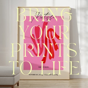 Pu&ograve; includere: Un poster rosa con il testo "BRING YOUR PRINTS TO LIFE" in un carattere giallo. Il poster include anche il testo "THE IT-OUTS" e "OCTOBER 20, 2023 - FEBRUARY 6, 2024". Il poster &egrave; incorniciato e appeso a una parete bianca.