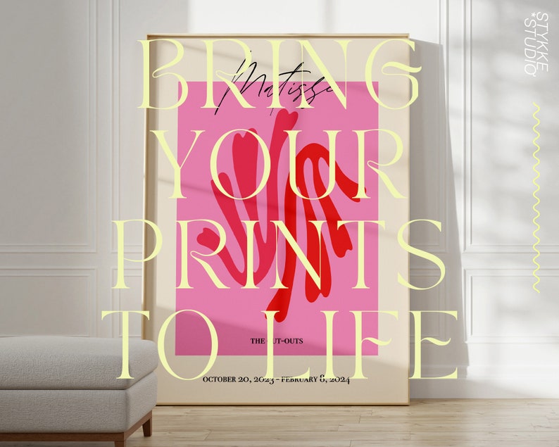 Pu&ograve; includere: Un poster rosa con il testo "BRING YOUR PRINTS TO LIFE" in un carattere giallo. Il poster include anche il testo "THE IT-OUTS" e "OCTOBER 20, 2023 - FEBRUARY 6, 2024". Il poster &egrave; incorniciato e appeso a una parete bianca.