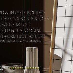May include: A white ceramic vase with a ribbed texture sits on a table in front of a large, framed grid. The frame is made of wood and has a light brown finish. The background is a dark brown wall with a light brown trim.