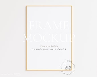 Könnte beinhalten: Ein goldener Rahmen-Mockup mit dem Text "FRAME MOCKUP", "DIN A 4 RATIO" und "CHANGEABLE WALL COLOR". Der Rahmen befindet sich an einer weißen Wand.