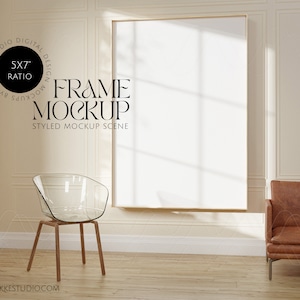 Puede incluir: Una escena de maqueta estilizada con un marco de imagen grande y vacío con un marco dorado, una silla de acrílico transparente y un sillón de cuero marrón. El marco está en una pared blanca con molduras decorativas. La habitación tiene un piso de madera clara. El texto "FRAME MOCKUP" y "STYLED MOCKUP SCENE" es visible debajo del marco. El texto "5x7" RATIO es visible en un círculo sobre el marco.