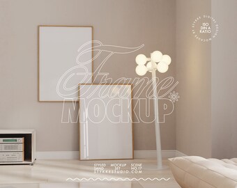 May include: A beige room with two framed pictures, a white floor lamp with multiple light bulbs, and a white couch. The text "Frame Mockup" is written in white on the wall.