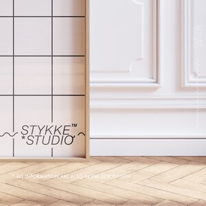 May include: A framed print with a black and white grid pattern and the text "STYKKE&trade; *STUDIO*" in black. The frame is made of wood and has a light brown finish. The print is sitting on a wooden floor with a herringbone pattern.