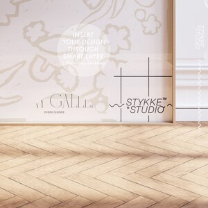 May include: A white wall with a floral pattern and a framed image with a grid pattern and the text "STYKKE&trade; *STUDIO*" and "STYKKE STUDIO". The wall is next to a wooden floor with a herringbone pattern.