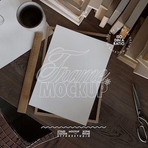 Maqueta de póster de papel DIN A sobre marco de madera colocado sobre una mesa desordenada, maqueta de impresión artística, maqueta de marco de impresiones digitales, maqueta de primer plano de un amante de los libros