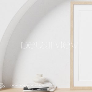 May include: A white ceramic vase with a textured surface sits on a white shelf with a framed picture and a stack of books. The text "detail view" is written in white on a white background.