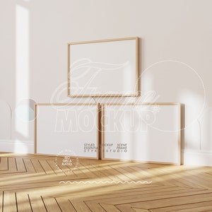 May include: Two wooden picture frames with white mats are leaning against a white wall. The frames are empty and ready for your photos or artwork. The frames are in a minimalist style and would look great in any home.