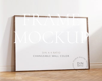 Puede incluir: Una maqueta de marco de madera marrón con fondo blanco. El marco está sobre un suelo de madera. El texto "FRAME MOCKUP" está en la parte superior del marco. El texto "DIN A 4 RATIO" y "CHANGEABLE WALL COLOR" está debajo del marco. El texto "STUDIO DIGITAL DESIGN" está en un círculo en la esquina inferior derecha del marco.
