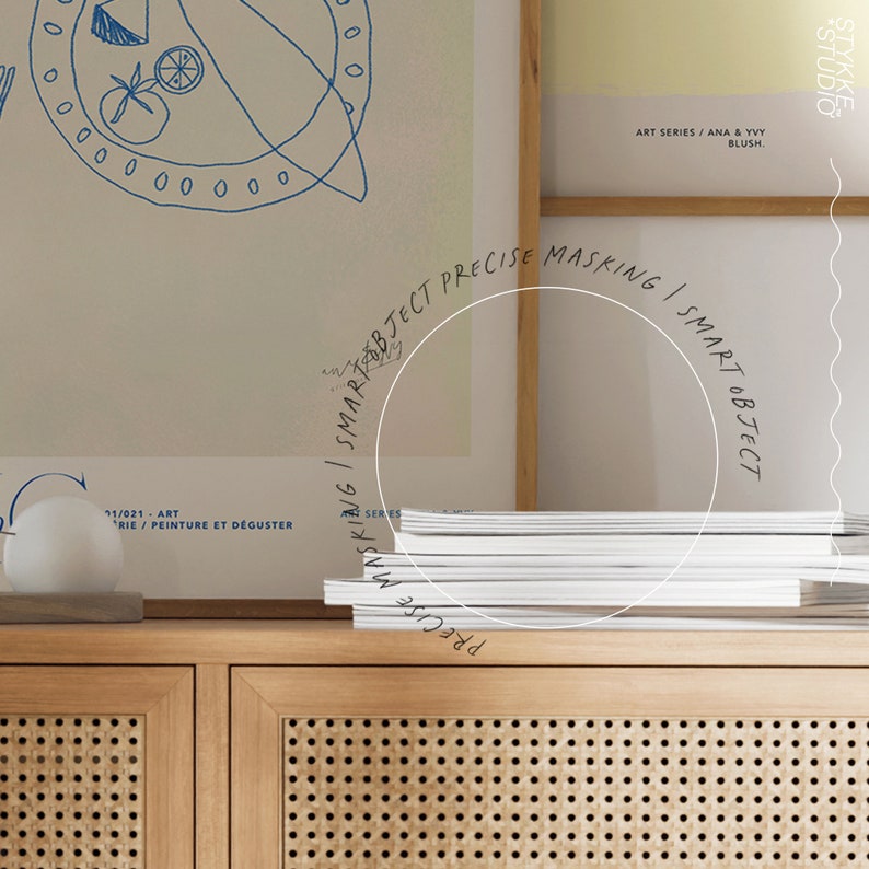 Puede incluir: Un mueble de madera clara con frente tejido exhibe una pila de revistas blancas. Arriba, impresiones art&iacute;sticas enmarcadas muestran dibujos lineales azules. El texto en la impresi&oacute;n art&iacute;stica dice "ART SERIES / ANA & YVY BLUSH". Una esfera blanca se encuentra en el mueble.