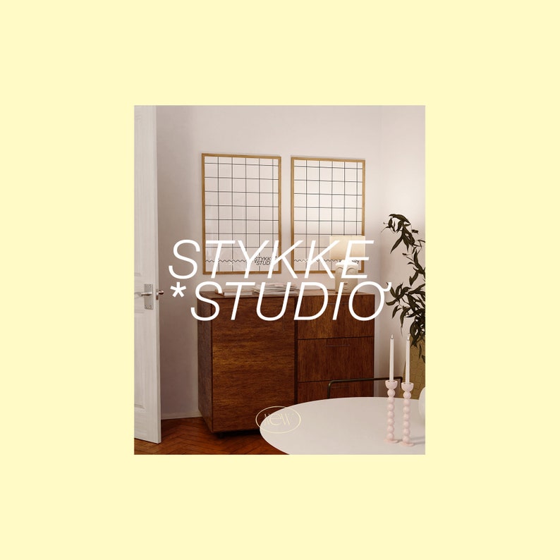 May include: A white room with two square framed mirrors with a grid pattern. A wooden dresser with two drawers is in front of the mirrors. A table with a white top is in front of the dresser. A pink candle holder with three candles is on the table. A plant is in the corner of the room. The text "STYKKE STUDIO" is in the center of the image.
