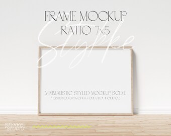 Puede incluir: Una maqueta de marco de madera clara con fondo blanco. El marco está sobre un suelo de madera clara contra una pared blanca. El texto "FRAME MOCKUP RATIO 7x5" está en la parte superior de la imagen. El texto "MINIMALISTIC STYLED MOCKUP SCENE *Displayed artwork & fonts not included" está en la parte inferior de la imagen.