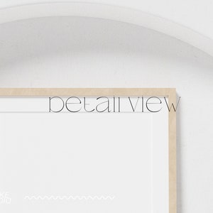 May include: A close-up of a wooden picture frame with a white mat and a white background. The frame is on a white wall. The text "detail view" is visible in the image.