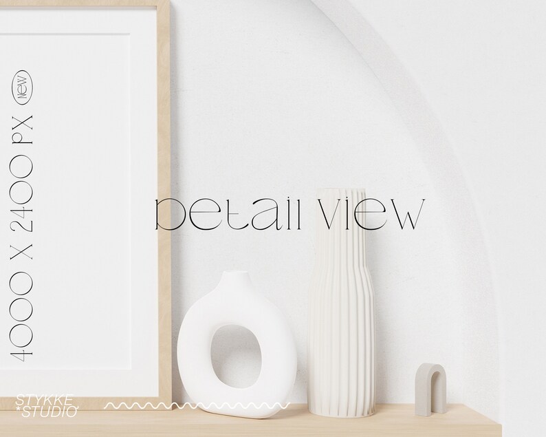 May include: A white ceramic vase with a ribbed texture, a white ceramic ring-shaped vase, and a gray arch-shaped sculpture on a light wood shelf. The text "detail view" is written in black on a white wall.
