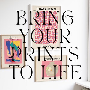 May include: Three framed prints on a white wall. The top print features a pink and blue floral pattern with the text "FLOWER MARKET OTTAWA POTTERY WORKSHOP". The middle print features a colorful abstract design with the text "Metriska THE ARTIST". The bottom print features a pink and beige illustration of a pot with the text "BRING YOUR PRINTS TO LIFE".