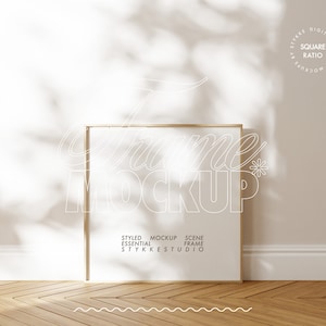 Może przedstawiać: Makieta złotej ramki na białym tle i drewnianej podłodze. Ramka jest kwadratowa i ma prosty design. Tekst "Styled Essential Mockup Scene Frame STYKKE STUDIO" jest wydrukowany pod ramką.