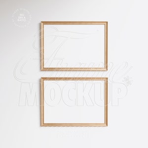 May include: Two gold picture frames with white mounts on a white wall. The frames are stacked on top of each other. The top frame is slightly larger than the bottom frame.