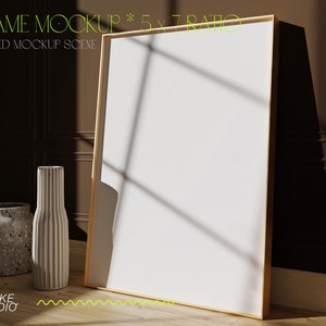 May include: A white frame mockup with a 5x7 ratio, styled with two vases on a wooden floor. The frame is leaning against a brown wall with white trim.