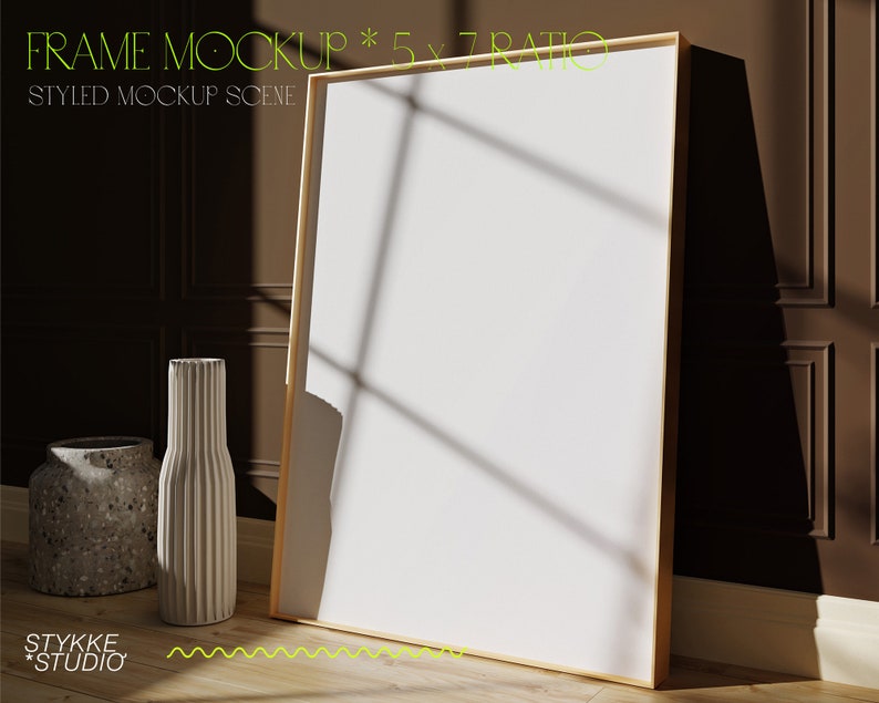May include: A white frame mockup with a 5x7 ratio, styled with two vases on a wooden floor. The frame is leaning against a brown wall with white trim.