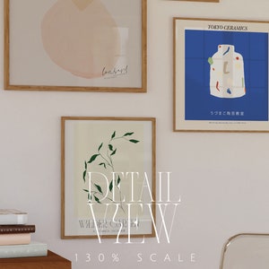 May include: Three framed art prints with a white background. The print on the left features a pink watercolor design with the word "Conserved" written in black. The print in the center features a green leafy branch. The print on the right features a blue background with a white ceramic vase with colorful geometric shapes. The text "TOKYO CERAMICS" is at the top of the print. The text "うづまこ陶芸教室" is at the bottom of the print. The text "*STUDIO" and "STYKKE" are written vertically on the right side of the image.