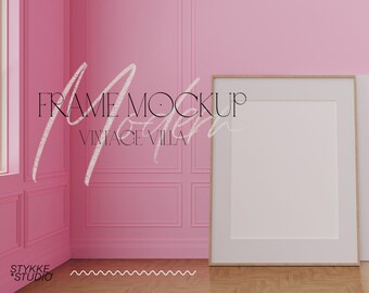以下が含まれることがあります： ピンクの部屋に白いフレームのモックアップがあります。壁には「FRAME MOCKUP VINTAGE VILLA」という黒い文字が書かれています。