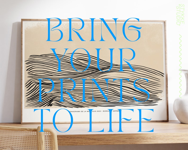 Puede incluir: Una impresi&oacute;n enmarcada con un dise&ntilde;o abstracto en blanco y negro de l&iacute;neas onduladas. La impresi&oacute;n tiene el texto "BRING YOUR PRINTS TO LIFE" en letras azules. La impresi&oacute;n est&aacute; sobre una mesa de madera con una silla.