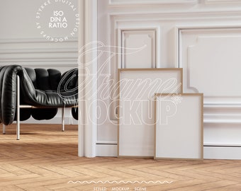 May include: Two empty picture frames with a wooden frame, sitting on a wooden floor in a room with white walls and a black leather chair. The frames are stacked on top of each other, with the larger frame in the back and the smaller frame in the front. The frames are both oriented vertically.