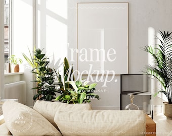 May include: A white frame mockup in a living room setting with a couch, plants, and a side table. The frame is hanging on a white wall.