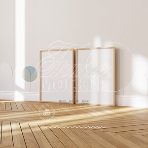 Peut inclure: Deux cadres photo en bois avec des passe-partout blancs sont appuyés contre un mur blanc. Les cadres sont vides et prêts à accueillir vos photos ou vos œuvres d'art. Les cadres sont dans un décor d'intérieur moderne avec un sol en bois.
