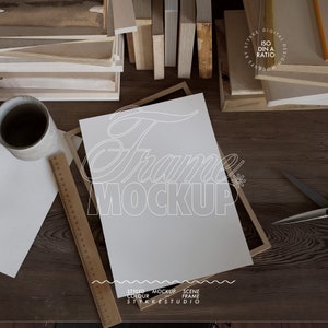 Maqueta de póster DIN A sobre marco de madera sobre una mesa desordenada, maqueta de impresión artística, maqueta de marco para impresiones digitales, maqueta de amante de los libros en primer plano