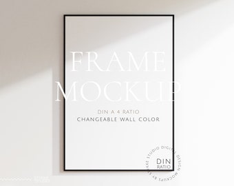 Könnte beinhalten: Ein schwarzer Rahmen-Mockup mit weißem Hintergrund. Der Rahmen befindet sich an einer weißen Wand mit Schatten. Der Text "FRAME MOCKUP" ist in Weiß auf dem Rahmen geschrieben. Der Text "DIN A 4 RATIO" und "CHANGEABLE WALL COLOR" ist in Schwarz auf dem Rahmen geschrieben. Der Text "KKE STUDIO DIGITAL DESIGN MOCKUPS BY" und "DIN RATIO" ist in Schwarz auf einem weißen Kreis geschrieben.