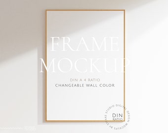 Puede incluir: Una maqueta de marco dorado con fondo blanco. El texto "FRAME MOCKUP" está escrito en blanco en el marco. El texto "DIN A 4 RATIO" y "CHANGEABLE WALL COLOR" está escrito en negro debajo del marco.