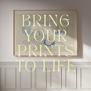 May include: A framed print featuring a blue and white abstract design. The print is displayed on a white wall with white panelling. The text "BRING YOUR PRINTS TO LIFE" is written in yellow lettering below the print.