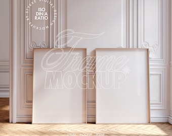 May include: Two empty picture frames with wooden frames are leaning against a white wall with ornate molding. The frames are in a room with a wooden floor.