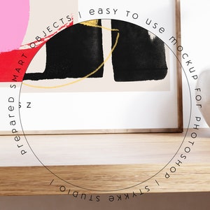 Puede incluir: Una pintura abstracta enmarcada con pintura negra, blanca, roja y amarilla. El marco est&aacute; sobre una superficie de madera con un jarr&oacute;n blanco y una superposici&oacute;n de texto que dice "prepared smart objects | easy to use mockup for photoshop | styke studio".