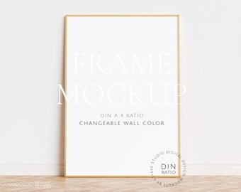 Könnte beinhalten: Ein goldener Rahmen-Mockup mit weißem Hintergrund. Der Rahmen steht auf einem Holzboden. Der Text "FRAME MOCKUP" ist in Weiß auf dem Rahmen geschrieben. Der Text "DIN A 4 RATIO" und "CHANGEABLE WALL COLOR" ist in Schwarz auf dem Rahmen geschrieben. Der Text "YKKE STUDIO DIGITAL DESIGN MOCKUPS BY" und "DIN RATIO" ist in Schwarz auf einem Kreis in der unteren rechten Ecke des Rahmens geschrieben.