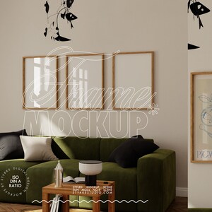 Op de afbeelding: Een mockup van vier houten fotolijsten die aan een muur hangen boven een groene fluwelen bank. De lijsten zijn leeg en klaar voor uw ontwerp. De bank staat in een woonkamer met een houten salontafel en een zwart-wit gestreept tapijt.