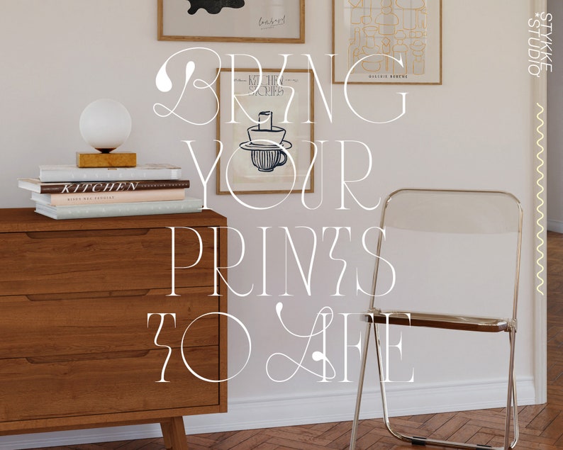 May include: A white dresser with three drawers and a white chair with a clear plastic seat. The dresser is decorated with books and a lamp. The wall behind the dresser is white and has two framed prints hanging on it. The text "BRING YOUR PRINTS TO LIFE" is written in white on the wall.