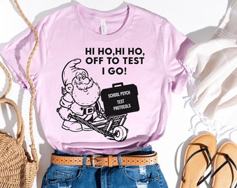 May include: A pink t-shirt with a black and white illustration of a gnome pushing a wheelbarrow with the text "HI HO, HI HO, OFF TO TEST I GO!" and "SCHOOL PSYCH TEST PROTOCOLS" on the side of the wheelbarrow.