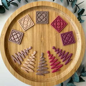 Puede incluir: Surtido de pendientes de arcilla polimérica en varios tonos de marrón y rosa. Los pendientes presentan un diseño floral y un diseño de árbol ondulado y abstracto.