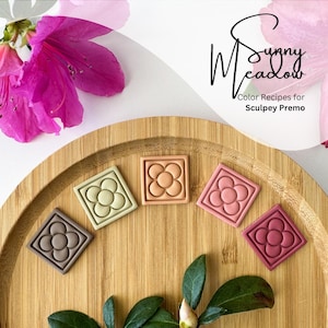 Może przedstawiać: Pięć kwadratów z polimerowej gliny z wzorem kwiatu w różnych kolorach: brązowym, zielonym, brzoskwiniowym, różowym i czerwonym. Kwadraty znajdują się na drewnianej powierzchni. W tle widoczny jest tekst "Sunny Meadow" i "Color Recipes for Sculpey Premo".