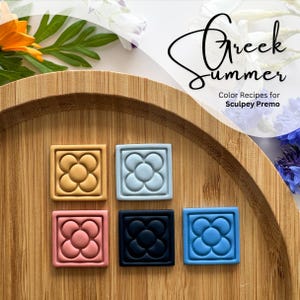 Könnte beinhalten: Fünf Polymer Clay-Fliesen mit einem Blumendesign in verschiedenen Farben. Die Farben sind Gelb, Blau, Rosa, Schwarz und Hellblau. Die Fliesen befinden sich auf einer Holzoberfläche. Der Text "Greek Summer" und "Color Recipes for Sculpey Premo" ist im Bild sichtbar.