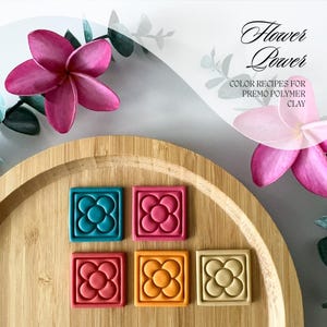 May include: Four polymer clay squares with a flower design in teal, red, orange, and beige. The squares are arranged in two rows of two on a wooden surface. The text "Flower Power" and "Color Recipes for Premo Polymer Clay" is written in white on a light gray background.